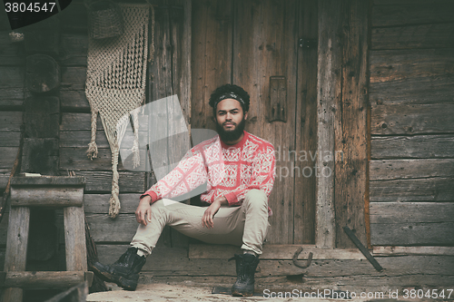 Image of portrait of young hipster in front of wooden house