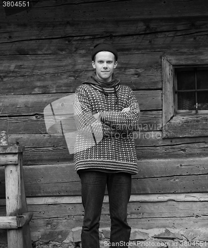 Image of young hipster in front of wooden house