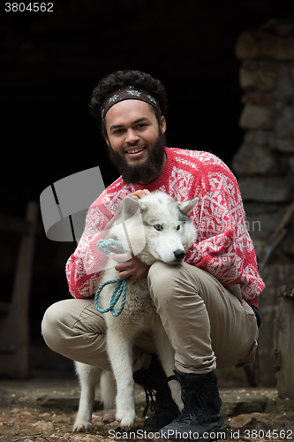 Image of hipster with dog in front of wooden house