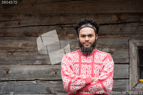 Image of portrait of young hipster in front of wooden house