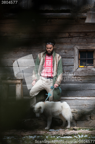 Image of hipster with dog in front of wooden house