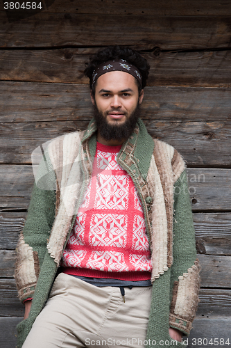 Image of portrait of young hipster in front of wooden house