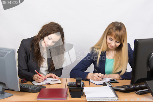 Image of Two business women working in the office with one desk