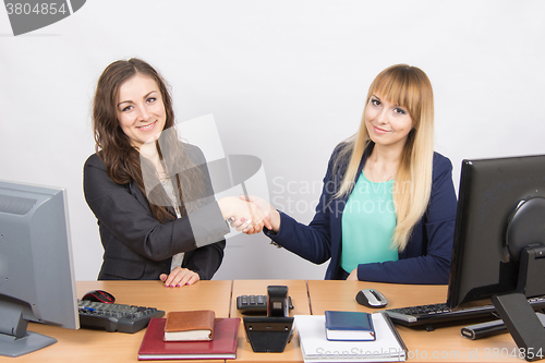 Image of Two young girls acquainted shake hands and looked into the frame