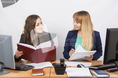 Image of Two business rivals girls look at each other while sitting at a desk