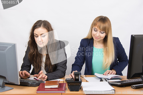 Image of Two young business women working in the office at the workplace at the same table