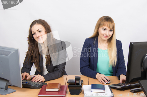 Image of Two young girls working at the computer sitting at a table in the office