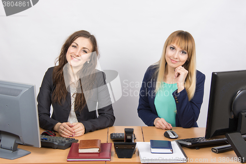 Image of Two young girls sitting at a table in the office and looking at the frame