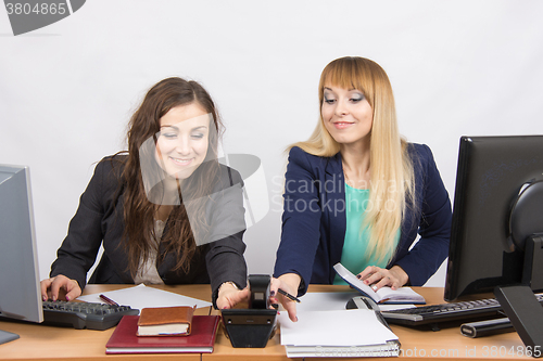 Image of Young girls in the office at the same time pull the hand to take the phone rang