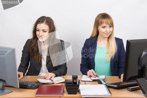 Image of Two business women working in the office with one desk