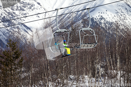 Image of Father and daughter on chair-lift at nice sunny day