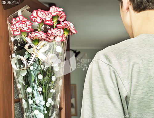 Image of A young man with a bouquet of flowers in his hands.