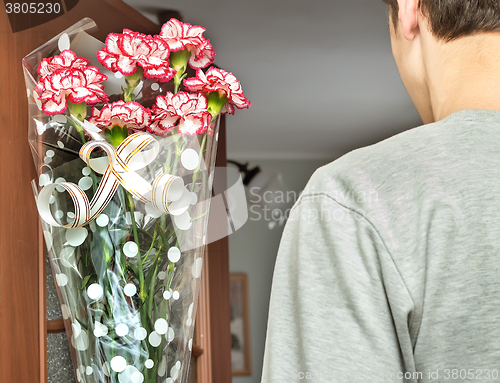 Image of A young man with a bouquet of flowers in his hands.