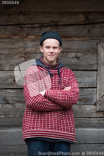 Image of young hipster in front of wooden house