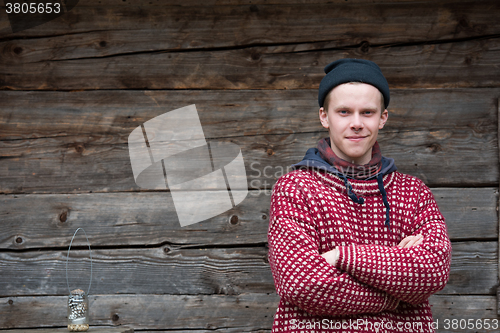 Image of young hipster in front of wooden house