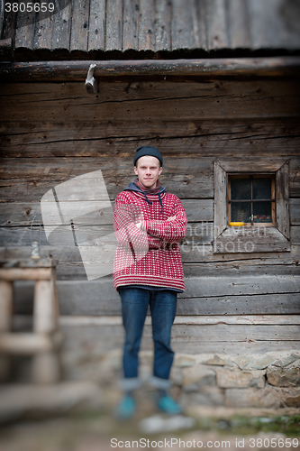 Image of young hipster in front of wooden house