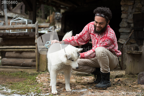 Image of hipster with dog in front of wooden house