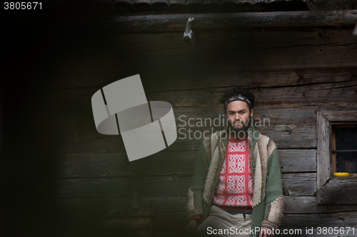 Image of portrait of young hipster in front of wooden house