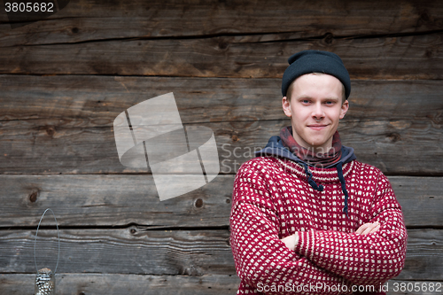 Image of young hipster in front of wooden house