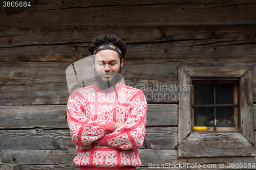 Image of portrait of young hipster in front of wooden house