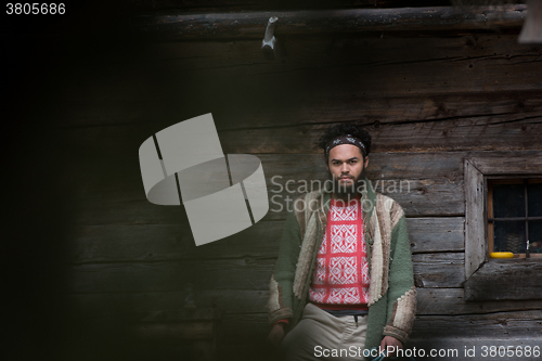 Image of portrait of young hipster in front of wooden house