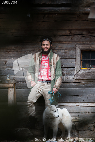 Image of hipster with dog in front of wooden house