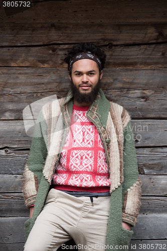 Image of portrait of young hipster in front of wooden house