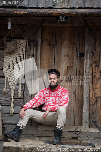 Image of portrait of young hipster in front of wooden house