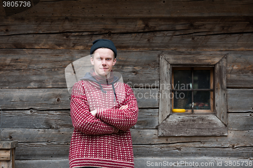 Image of young hipster in front of wooden house