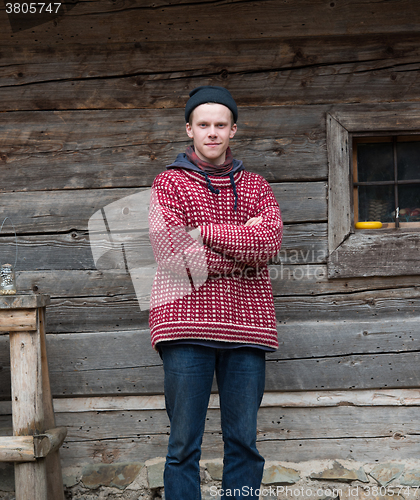 Image of young hipster in front of wooden house