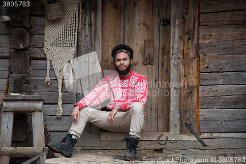 Image of portrait of young hipster in front of wooden house