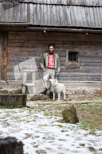 Image of hipster with dog in front of wooden house