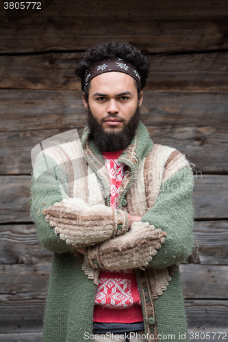 Image of portrait of young hipster in front of wooden house