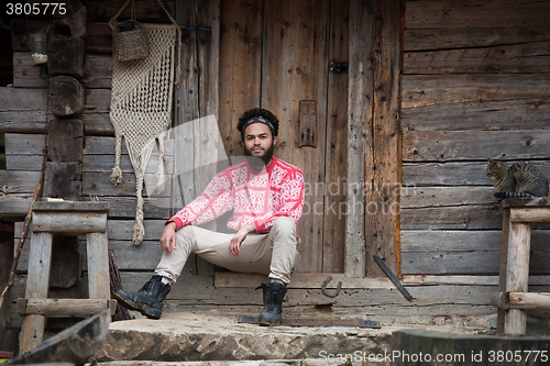 Image of portrait of young hipster in front of wooden house