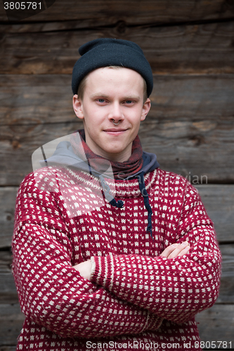 Image of young hipster in front of wooden house