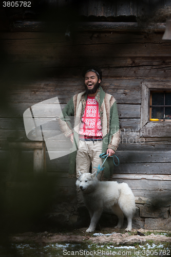 Image of hipster with dog in front of wooden house