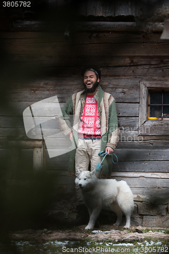 Image of hipster with dog in front of wooden house