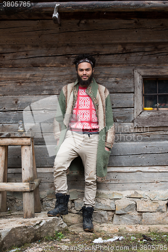 Image of portrait of young hipster in front of wooden house