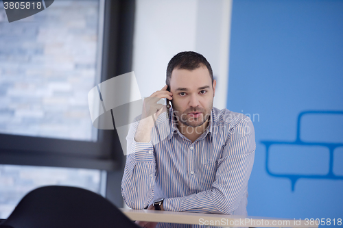 Image of business man talking by phone in office
