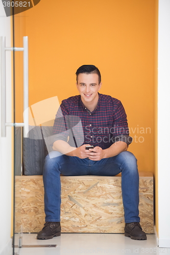 Image of man in crative box working on smart phone