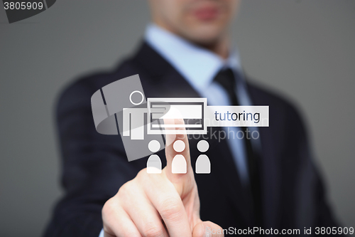 Image of Businessman pressing button on touch screen interface and select Tutoring. Business concept.