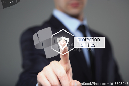 Image of  technology and internet concept - businessman pressing security button on virtual screens. protection of files