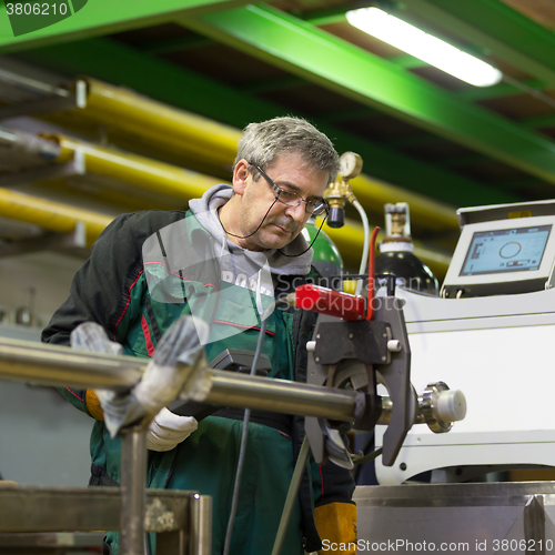 Image of Industrial worker setting orbital welding machine.