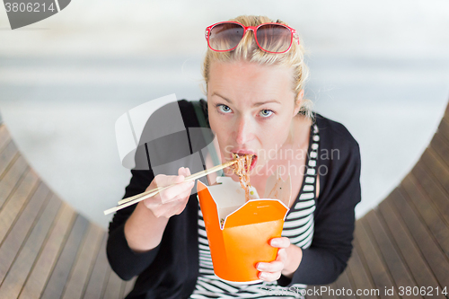 Image of Woman eating Chinese take-away noodels.