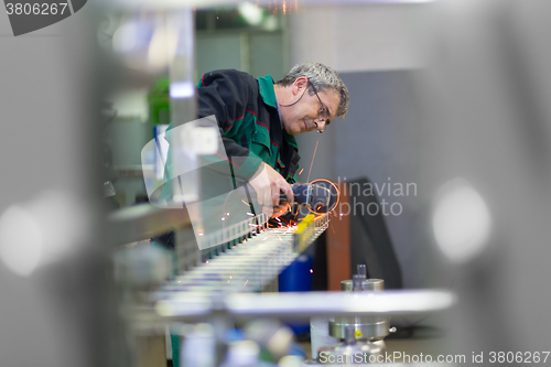 Image of Industrial worker  grinding in manufacturing plant.