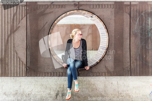 Image of Young urban woman sitting in city park.