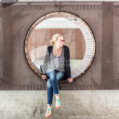 Image of Young urban woman sitting in city park.