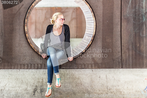 Image of Young urban woman sitting in city park.