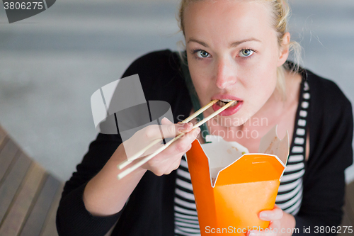 Image of Woman eating Chinese take-away noodels.