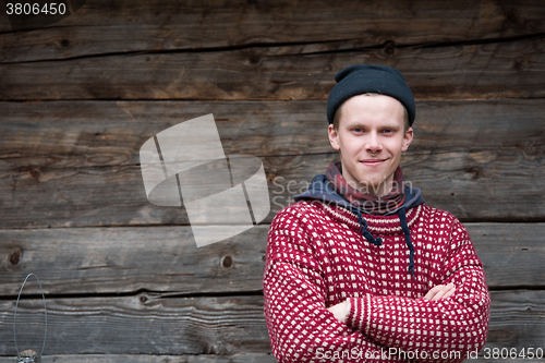 Image of young hipster in front of wooden house